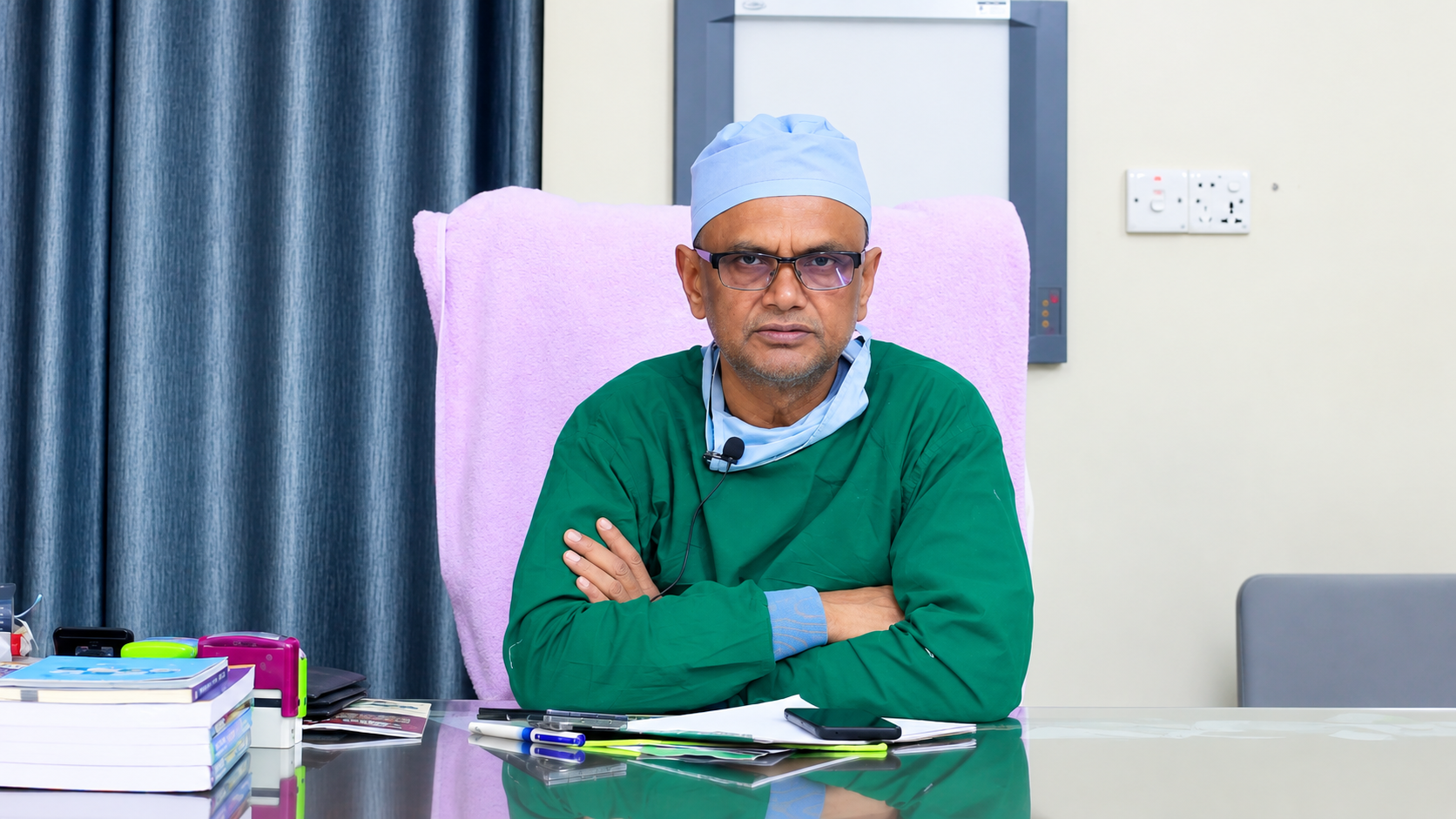 প্রফেসর ডা. এ. এন. এম. মোজাম্মেল হক সার্জিক্যাল পোশাকে চেম্বারে বসে আছেন